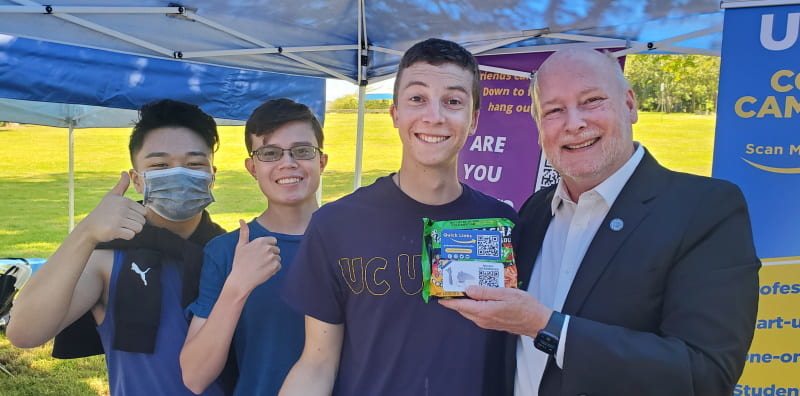 UCI Chancellor Howard Gillman (far right) poses with students as he hands out free ramen at the UCI ANTrepreneur Center's booth on Ring Road